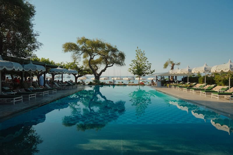 Relaxing poolside view with trees and lounge chairs at Jayney Travels.